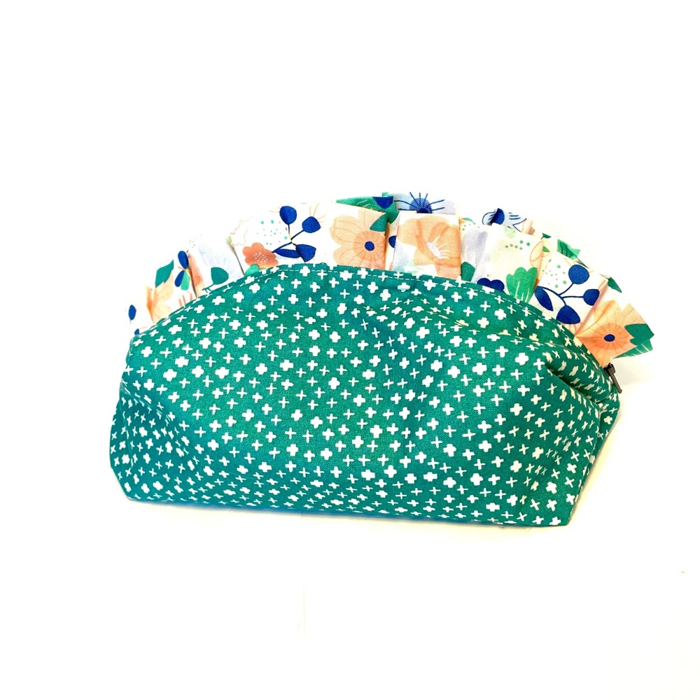 Teal travel back with pink floral interior, ruffle, and contrasting gray zipper